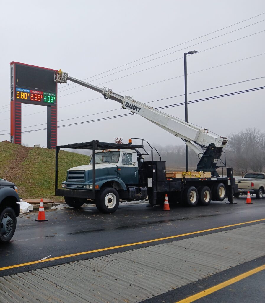 Gas Station Pricer Digital Sign Getting Maintenance Done by man in Bucket on Maintenance Truck